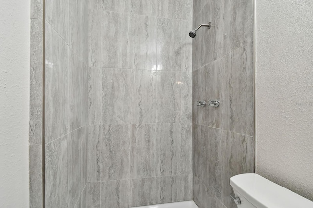 bathroom featuring toilet and a tile shower