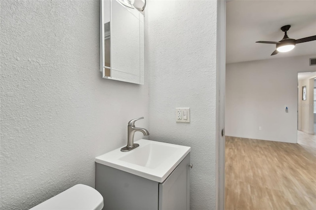 bathroom featuring toilet, vanity, hardwood / wood-style flooring, and ceiling fan