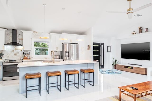 kitchen featuring white cabinets, sink, wall chimney range hood, pendant lighting, and appliances with stainless steel finishes