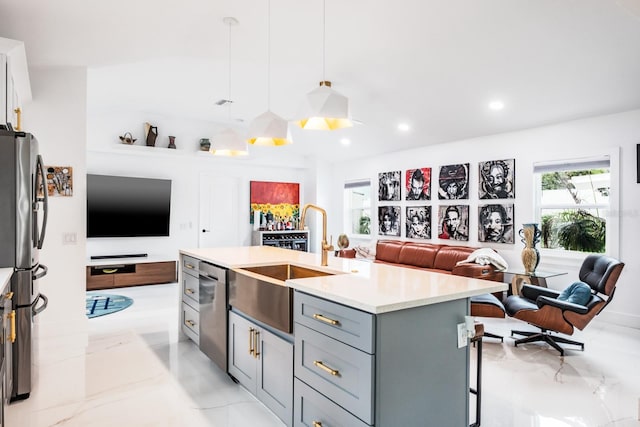 kitchen with stainless steel appliances, sink, a kitchen island with sink, gray cabinetry, and pendant lighting