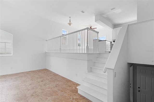 staircase with plenty of natural light and ceiling fan