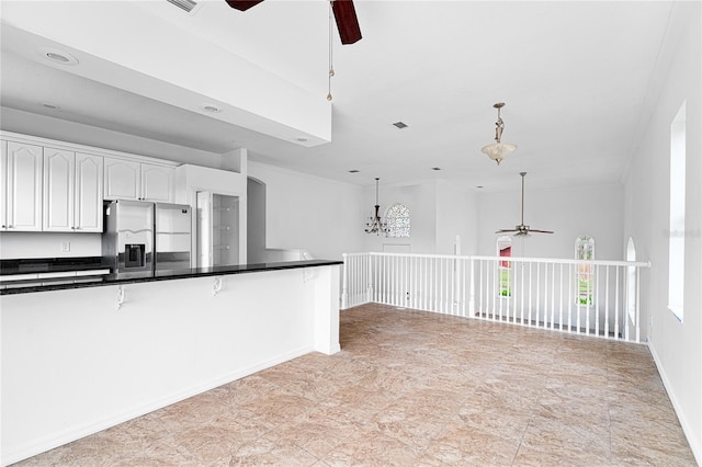 kitchen with white cabinets, stainless steel fridge, ceiling fan with notable chandelier, and hanging light fixtures