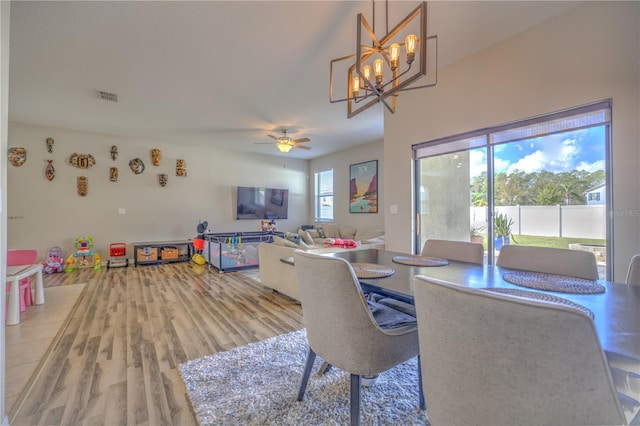 dining space featuring ceiling fan with notable chandelier and wood-type flooring