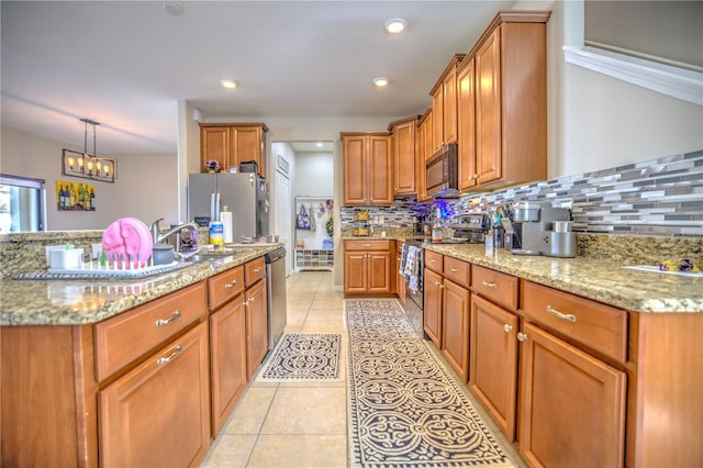 kitchen featuring stainless steel appliances, sink, light stone counters, and decorative backsplash