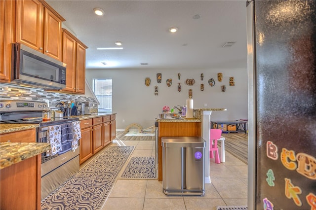 kitchen featuring stainless steel appliances, light tile patterned floors, backsplash, and light stone countertops