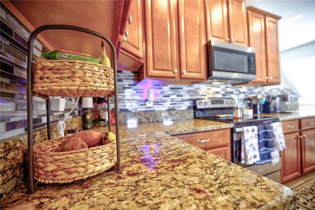 kitchen featuring stainless steel appliances, backsplash, and light stone countertops