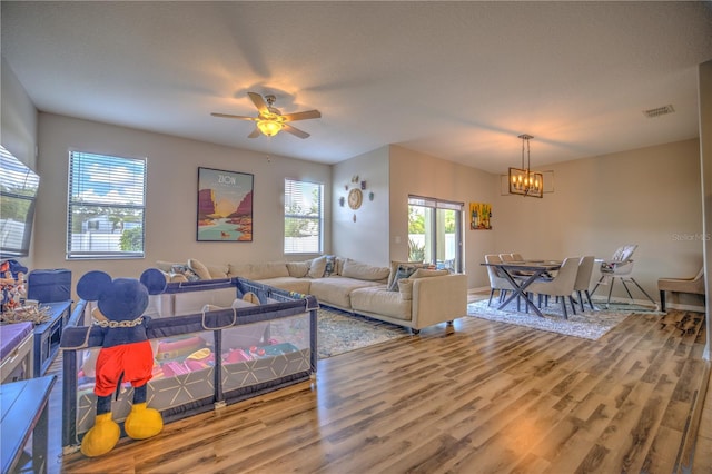 living room featuring a textured ceiling, hardwood / wood-style flooring, and ceiling fan with notable chandelier