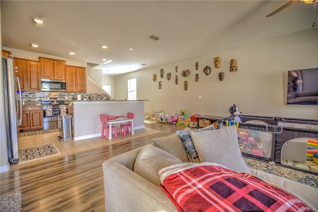 living room with light hardwood / wood-style floors and ceiling fan