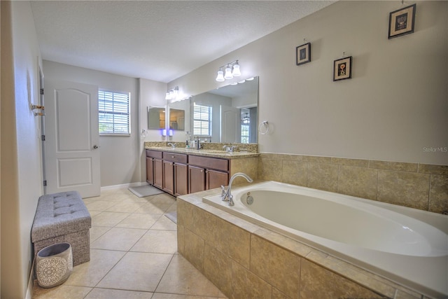 bathroom featuring tile patterned flooring, vanity, a textured ceiling, and tiled tub