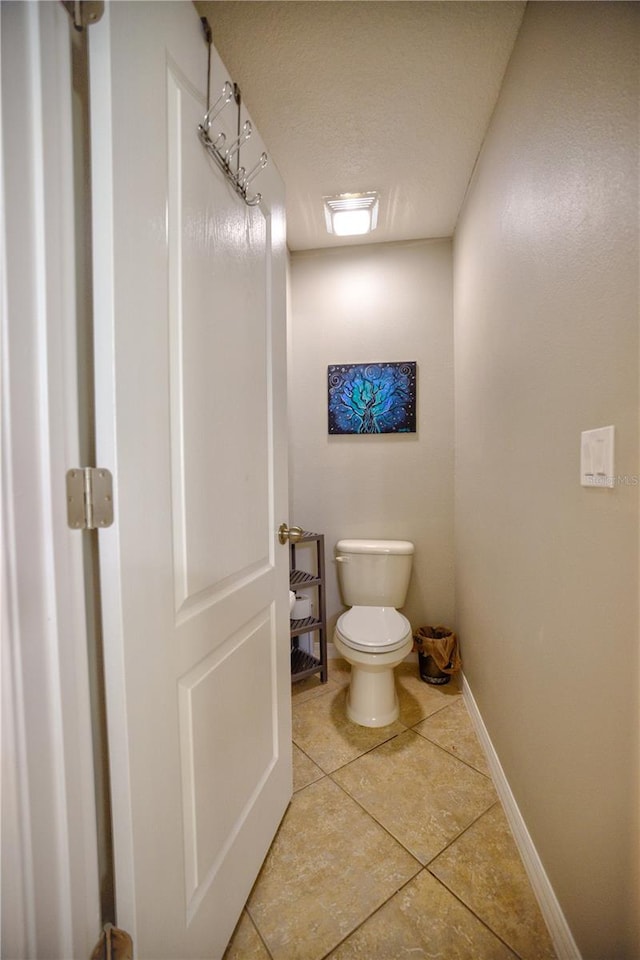 bathroom with tile patterned flooring, a textured ceiling, and toilet