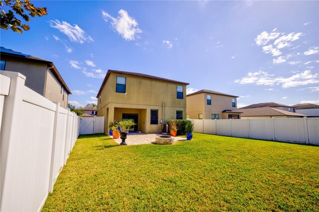 back of property with a patio, a yard, and a fire pit