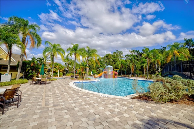 view of pool with pool water feature, a water slide, and a patio area