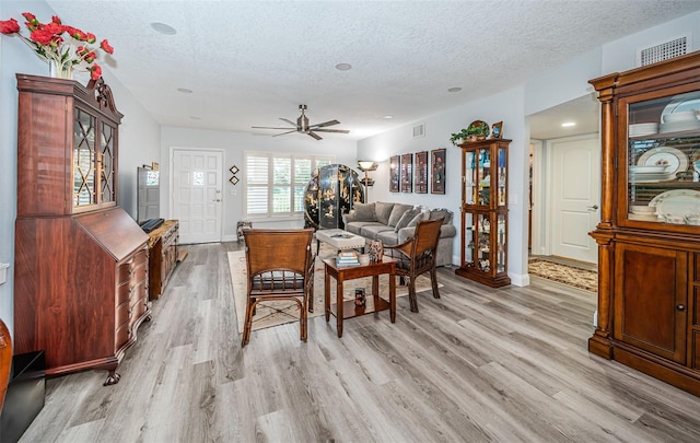 living room featuring a textured ceiling, light hardwood / wood-style flooring, and ceiling fan