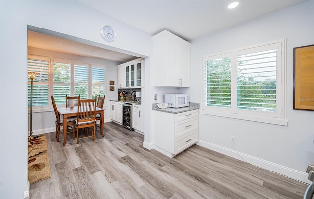 kitchen with white cabinetry, plenty of natural light, beverage cooler, and light wood-type flooring