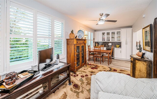 living room with light wood-type flooring, wine cooler, and ceiling fan