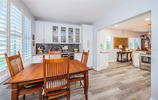 dining space with light wood-type flooring and beverage cooler