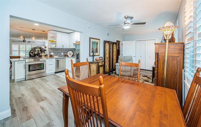 dining area featuring ceiling fan, light wood-type flooring, and a textured ceiling