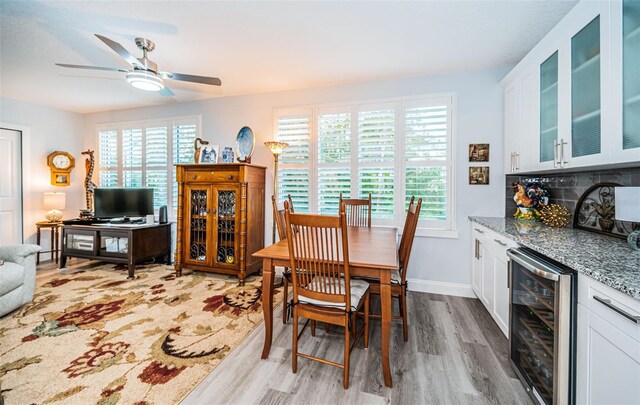 dining area with ceiling fan, light wood-type flooring, and beverage cooler