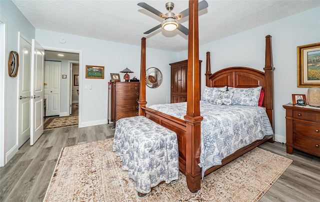 bedroom with a textured ceiling, light hardwood / wood-style flooring, and ceiling fan