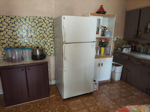 kitchen featuring dark brown cabinetry and white fridge