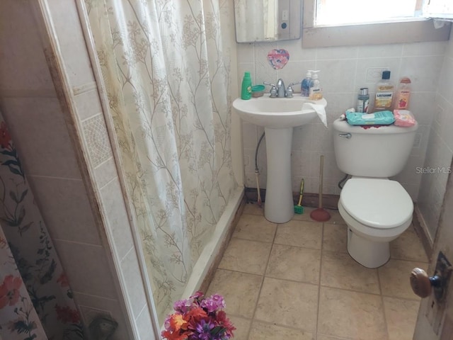 bathroom featuring tile walls, sink, a shower with shower curtain, tile patterned flooring, and toilet