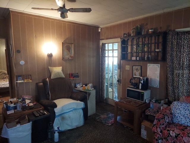 interior space with ornamental molding, wooden walls, and ceiling fan