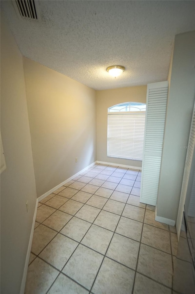 tiled empty room with a textured ceiling