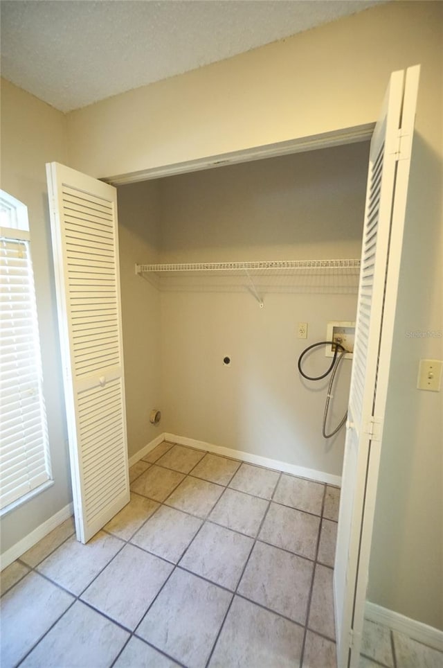 laundry room featuring light tile patterned floors, washer hookup, and a textured ceiling