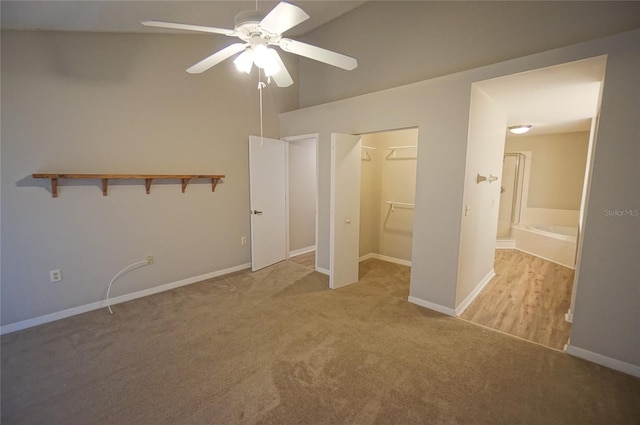 unfurnished bedroom with a walk in closet, ceiling fan, a closet, and light colored carpet