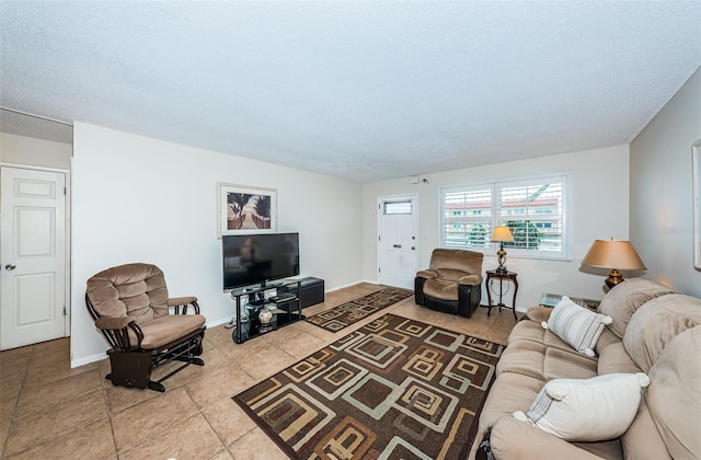 living area featuring light tile patterned floors, baseboards, and a textured ceiling