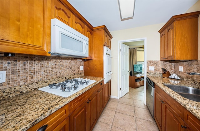 kitchen featuring white appliances, brown cabinetry, and a sink