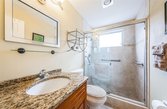 bathroom featuring vanity, toilet, and a shower with shower door