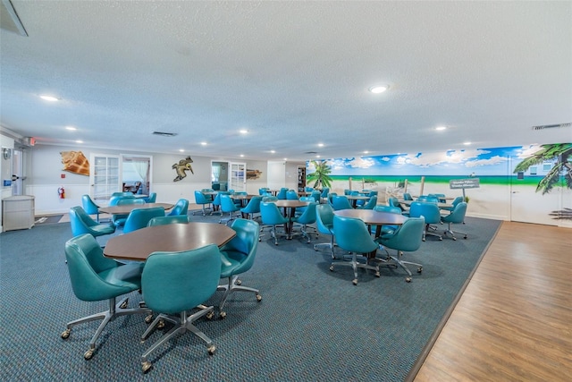 dining space with hardwood / wood-style floors and a textured ceiling