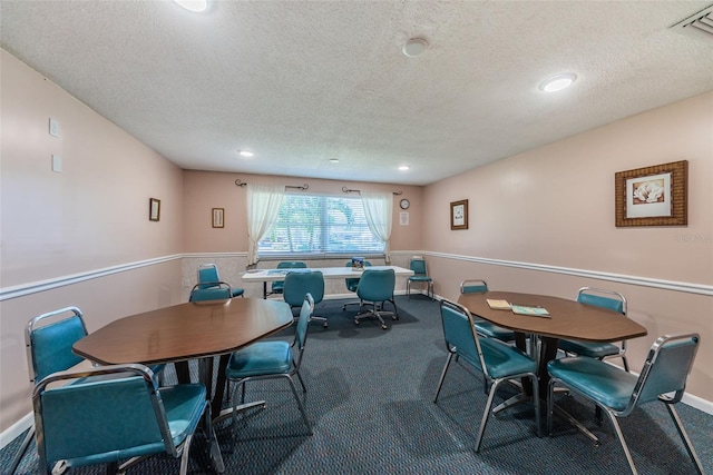 carpeted dining area with a textured ceiling