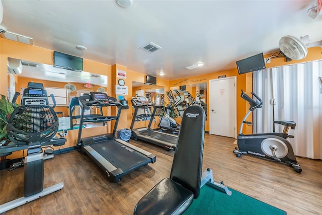 gym featuring a wall mounted air conditioner, visible vents, and wood finished floors