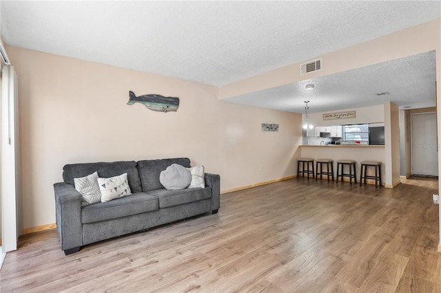 living room with a textured ceiling and light hardwood / wood-style floors