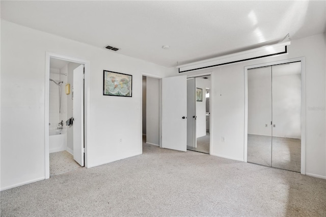 unfurnished bedroom featuring ensuite bathroom and light carpet