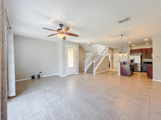 unfurnished living room featuring light tile patterned flooring and ceiling fan with notable chandelier