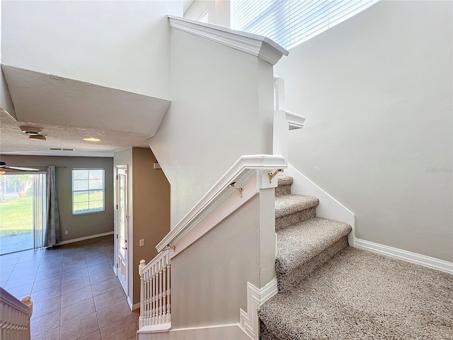 stairs with lofted ceiling, a textured ceiling, and tile patterned floors