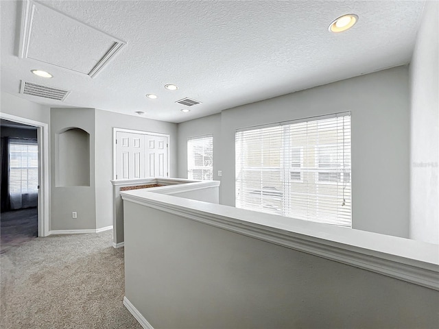 hall featuring a textured ceiling and light carpet