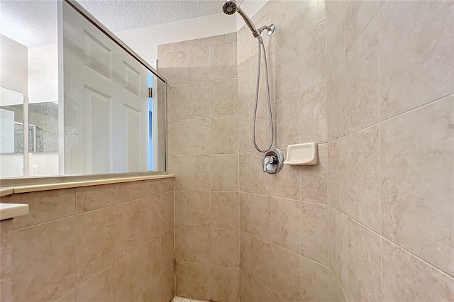 bathroom with a textured ceiling and a tile shower