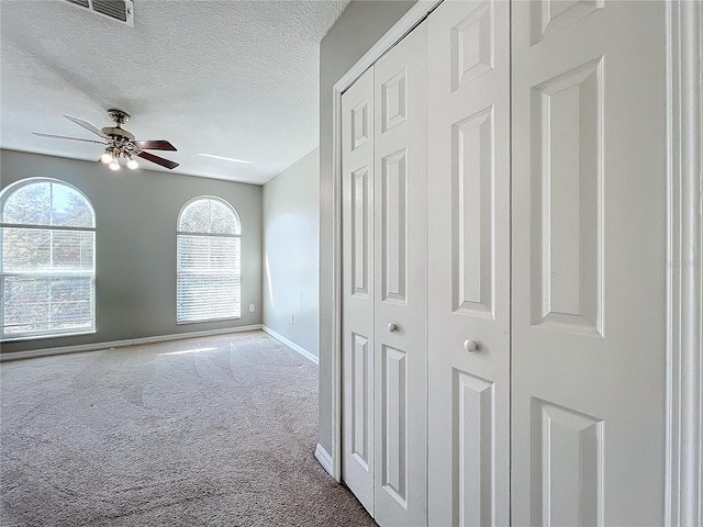 hallway featuring carpet flooring and a textured ceiling