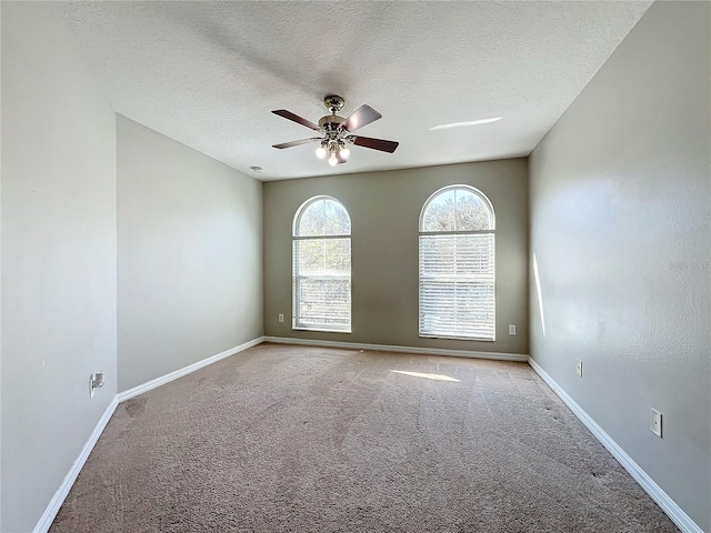 empty room with ceiling fan, light colored carpet, and a textured ceiling