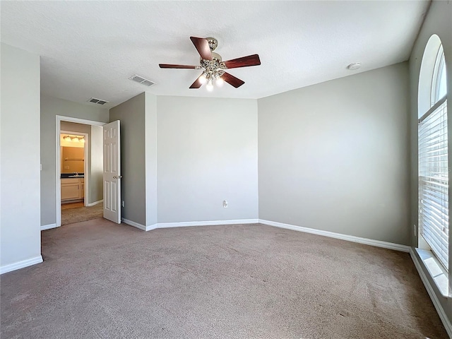 carpeted spare room featuring a textured ceiling and ceiling fan