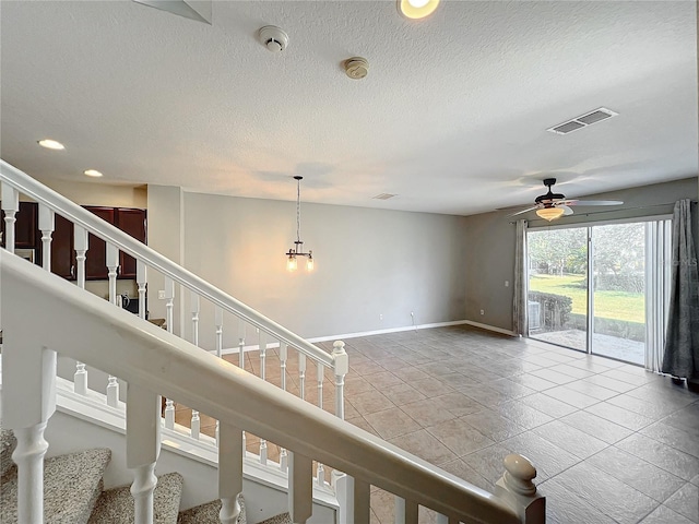 interior space with ceiling fan with notable chandelier and a textured ceiling