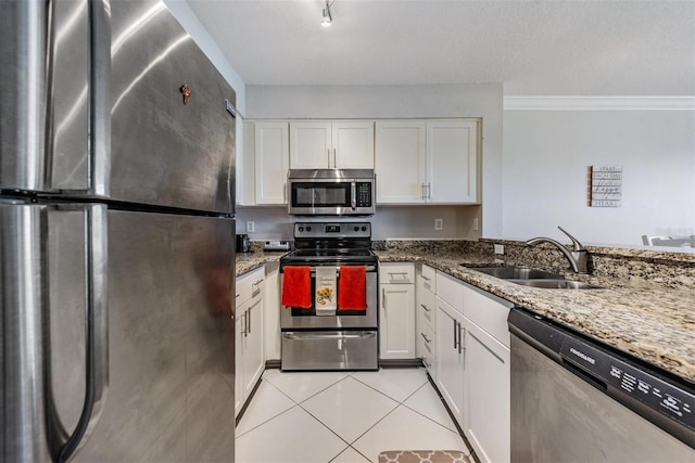 kitchen with white cabinetry, sink, light stone countertops, light tile patterned floors, and appliances with stainless steel finishes