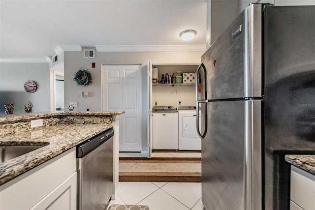 kitchen featuring light stone countertops, appliances with stainless steel finishes, light tile patterned floors, washing machine and clothes dryer, and white cabinets