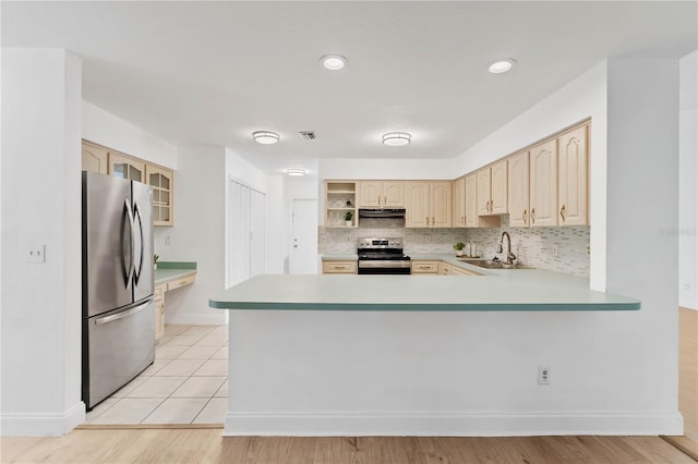 kitchen with stainless steel appliances, kitchen peninsula, sink, backsplash, and light wood-type flooring