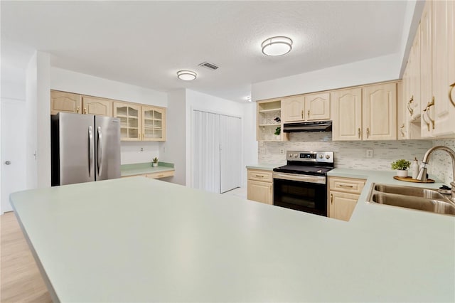 kitchen with sink, kitchen peninsula, appliances with stainless steel finishes, a textured ceiling, and light wood-type flooring