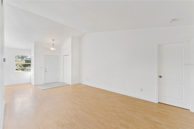 spare room with light hardwood / wood-style flooring and vaulted ceiling